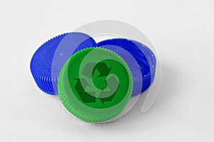 Plastic bottle caps with recycle symbol on white background - Concept of recyclable items and materials