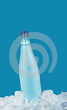 Plastic bottle of drinking water on ice over blue