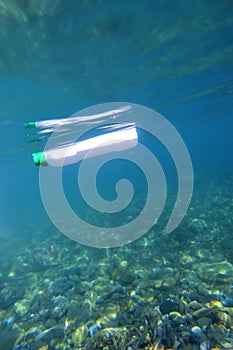 Plastic bottle floating in the sea, photo underwater with the seabed