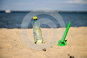 Plastic Bottle of fresh water is on the sand by the sea. Drinking water in bottle on sand on beach. Bottle of fresh