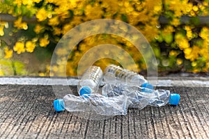 Plastic bottle garbage waste is thrown on the ground with blur green nature background.