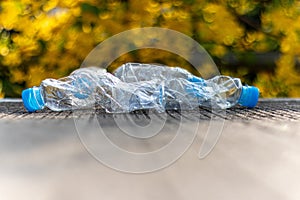 Plastic bottle garbage waste is thrown on the ground with blur green nature background. - concept reuse.