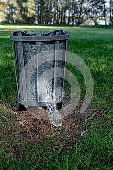 plastic bottle next to bin in a park