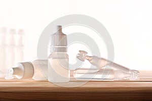 Plastic bottle and pipettes with eye medication on wooden table