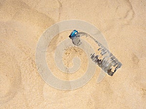 Plastic bottle on sandy beach, top view. Empty uncapped used plastic drinking water bottles piled up with sand.