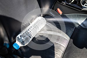 Plastic bottle of water placed on car seat and exposed to sun in sunny day,bottle of drinking water in car,sunlight,very hot,