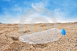 Plastic bottle of water in sand on tropical sandy beach