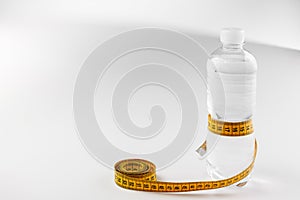 A plastic bottle with water wrapped in a yellow meter isolated on white background . Health concept. Bottled water for healthy