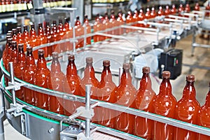 Plastic bottles with beer or carbonated beverage moving on conveyor