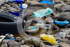 Plastic bottles and car tire in muddy oily water