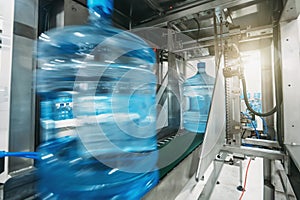 Plastic bottles with clean drinking water in factory on conveyor belt in blurred motion