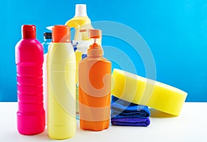 Plastic bottles of cleaning products set on white table