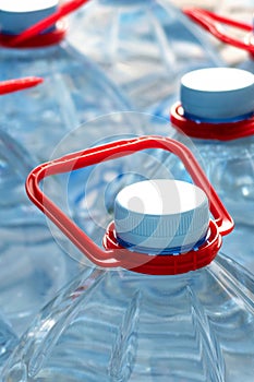 Plastic bottles with drinking water. Blue cover and red handle. 5 liter bottles. Selective focus