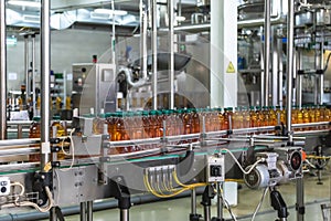 Plastic bottles with fresh organic juice on automatic conveyor belt or line in beverage factory or plant interior inside