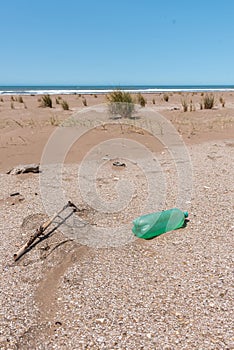 Plastic bottles lying on the sand near the beach and behind them you can see the horizon in the sea. Care of the earth