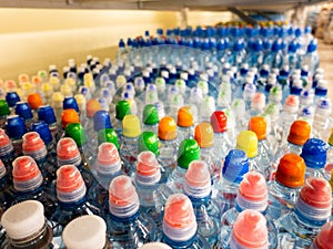 Plastic bottles with mineral water. Closeup on water bottles in raw and lines. Plastic bottles, colorful caps. Plastic bottles wit