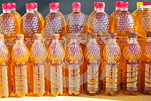 Plastic bottles of openwork yellow color with red stoppers standing in two rows. Vegetables, agriculture