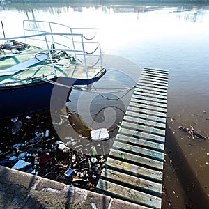 Plastic bottles, packages, trash in river near yacht. Illegal garbage dump, water pollution