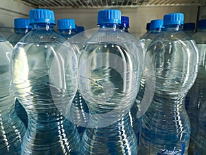 Plastic bottles with purified drinking water on shelf in fridge put up for sale shop