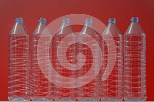 Plastic bottles on a red background as a symbol of ecological catastrophes.