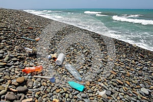 Plastic bottles rubbish on wild pebbles beach. Ocean and sea littering concept