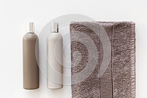 Plastic bottles of shampoo and body gel on towel isolated on white. Flat lay