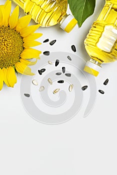 Plastic bottles with sunflower oil, fresh yellow sunflowers, sunflower seeds on gray background. Harvest time agriculture farming
