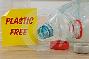 Plastic bottles and a yellow card with the words `Plastic Free` The concept of reducing the amount of use of plastic to care for t