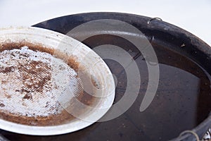 plastic bowl abandoned in a vase with stagnant water inside. close up view. mosquitoes in potential breeding ground