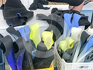 Plastic box, basket with multi-colored rubber diving flippers for swimming, diving equipment on board a box, boat, cruise liner