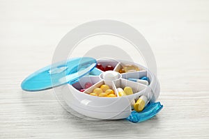 Plastic box with pills on white wooden table