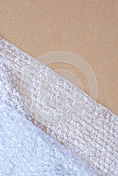 Plastic bubble wrap on brown cardboard paper sheet background in vertical frame, Top view with copy space