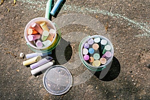Plastic bucket with chalk for drawing on asphalt. Multi-colored crayons for children`s drawings. Drawing with chalk on asphalt.