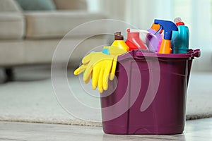 Plastic bucket with different cleaning products on floor indoors