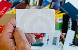 Plastic card in hand on blurred background of plastic customer cards