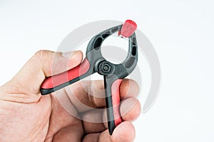 Plastic carpenters pinch tool in the hand above white background with copy space