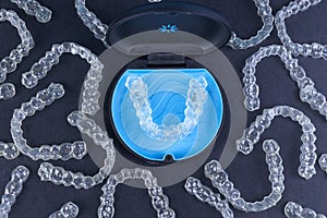 Plastic case with invisible transparent orthodontic retainers invisalign on black background. Aligner brackets or braces