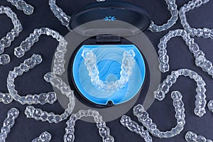Plastic case with invisible transparent orthodontic retainers invisalign on black background. Aligner brackets or braces photo