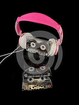 Plastic cassette and audio headphones. Music cassette on a black background. Concept: music, melomania, nastalgia