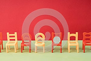 Plastic chairs are arranged in a row on a red background, on one of the chairs is the Russian ruble