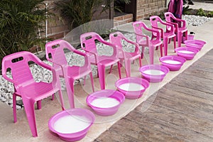 Plastic chairs with punch bowls arranged to do foot treatments for girls; spa theme children`s party
