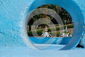 Plastic chairs and tables of an outdoor cafe visible from a blue hole