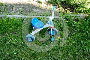 a plastic children's tricycle left in the yard on the lawn