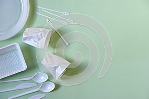 Plastic coffee cups, spoons, knives, stirrers, plate and box on green