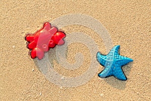 Plastic colored shapes for children play with sand on the beach. Baby plastic molds lying in the sand on the seabeach