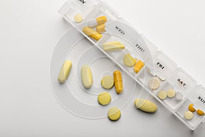 Plastic container with different pills on white background