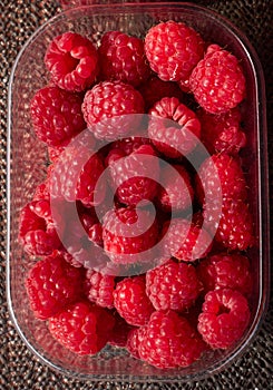 Plastic container full of fresh rasberries