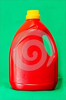 Plastic container for liquids, detergent, red color on a green background.