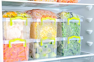 Plastic containers with deep frozen vegetables in refrigerator