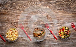 Plastic containers with delicious food on wooden background